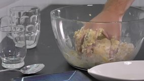 Person preparing cake in a glass bowl.. Close up footage of male hands kneading the dough