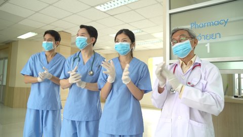 Asian healthcare workers doctor and nurse wearing protective face mask clapping hands or applauding hands in hospital after dealing with coronavirus covid-19 pandemic