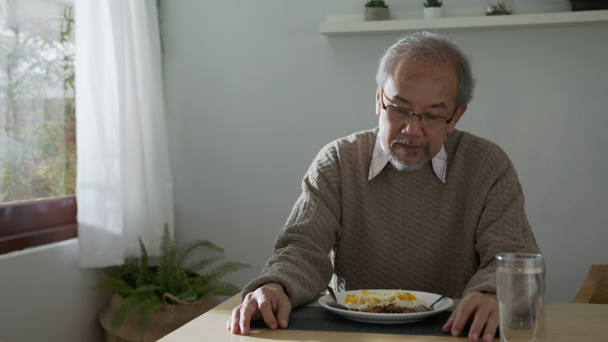 Medium shot : Sad old retired gray haired grandpa asian man sitting alone at table desk at window boring stay home self isolation quarantine feeling depress in problem mental health. Royalty-Free Stock Footage #1060432732