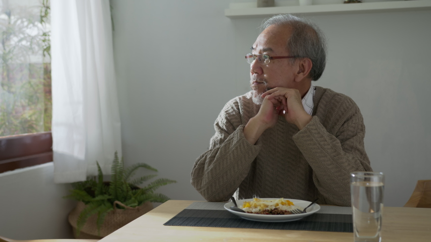 Medium shot : Sad old retired gray haired grandpa asian man sitting alone at table desk at window boring stay home self isolation quarantine feeling depress in problem mental health. Royalty-Free Stock Footage #1060432732