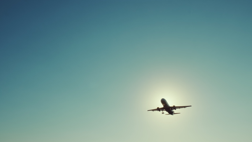 Large airliner with passengers on blue sky is landing on landing strip at airport of bright orange sunset on sunny summer day. Go Everywhere. Airplane flies in sky at sunset day lens flares. Travel Royalty-Free Stock Footage #1060433590