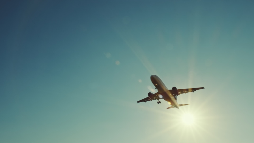 Large airliner with passengers on blue sky is landing on landing strip at airport of bright orange sunset on sunny summer day. Go Everywhere. Airplane flies in sky at sunset day lens flares. Travel Royalty-Free Stock Footage #1060433590