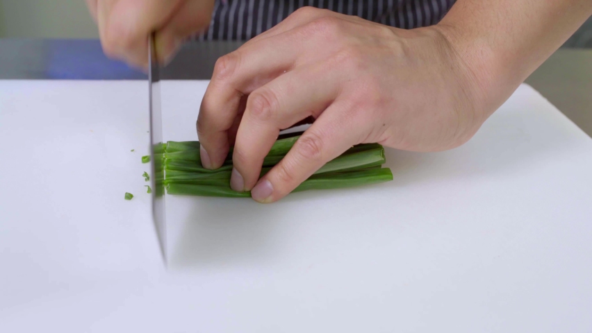 Slicing green beans on cutting board AND chef's knife on cutting board