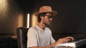 Conceptual shot of handsome stylish musician composing new song in modern sound recording studio. Attractive singer playing on midi piano