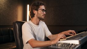 Young stylish musician feeling rhythm working on new music album in modern sound recording studio