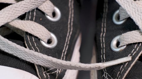 Close-up of rotating pair of black used sneakers with white laces. Sport shoes, youth fashion concept.