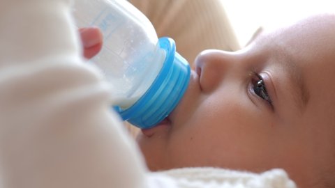 Closeup view of mother feeding her baby milk from bottle