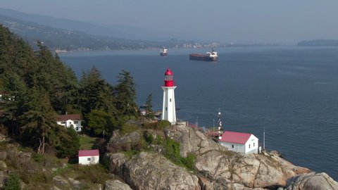 Aerial flyover shot of historical landmark Point Atkinson Lighthouse by day in West Vancouver, British Columbia, Canada.
