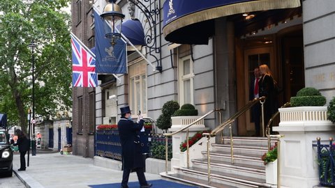 London. UK- 10.06.2020: a doorman of the London Ritz Hotel helping guests taking a selfie by the hotel entrance.