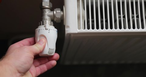 Turning down the heating adjusting radiator valve in a room