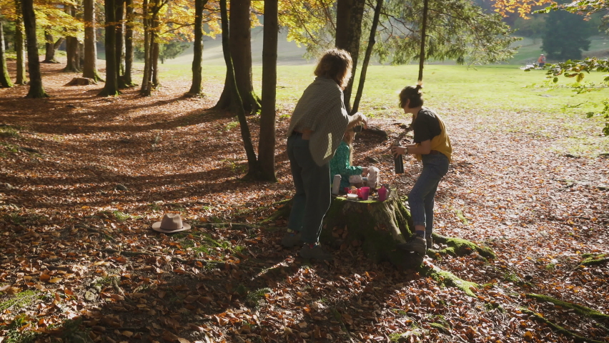 group of tourists women ehjoying an autumn forest picnic in the sunny october day
