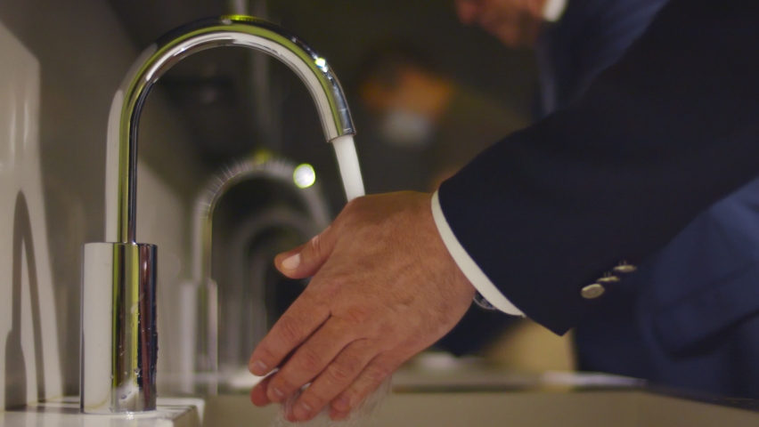 Close up of businessman washing hands in sink in public restroom. Entrepreneur disinfecting hands with soap and water after visiting office toilet Royalty-Free Stock Footage #1060452007