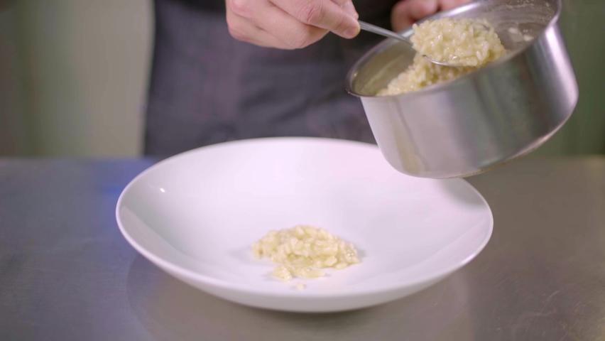 Chef placing risotto in stainless steel kitchen