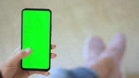 Handheld Camera: Back view of brunette holding chroma key green screen smartphone watching content. Gadgets and contemporary people concept.