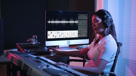 Music production studio. Producer. Woman working in the recording studio with computer and mixer creating music in sound recording studio. Music production.