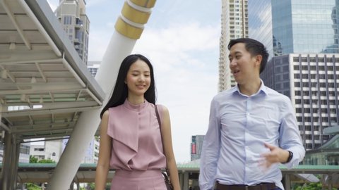 Young Asian business people discussing while walking near office buildings. Attractive Asia business woman and man talking - 4K High Quality Footage