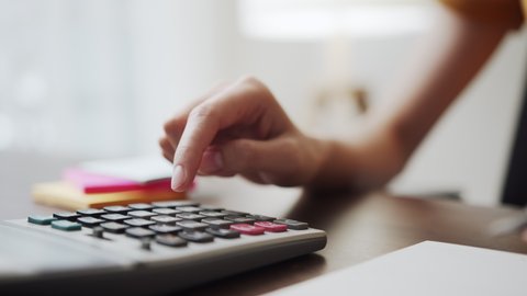 Hand press calculator to calculate income expenses and plans for spending money on home office.