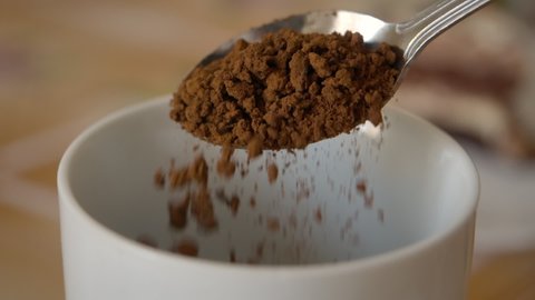 Instant Coffee Pieces Falling From Spoon in Slow Motion in Cup. Fresh Morning Hot Chocolate Close Up. Slow Motion. Coffee Powder Falling From Spoon. Closeup Morning Cocoa.