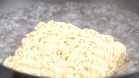 Woman put instant noodles in a boiling water. Junk food.
