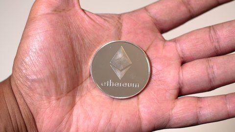 Black man hands closing around Ethereum coin