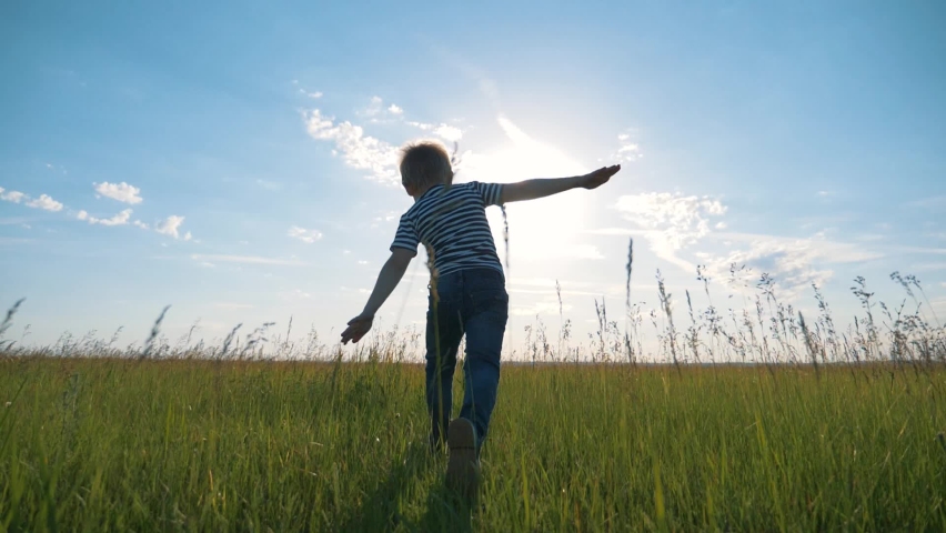Happy child in the park. Silhouette  run child at sunset. Happy child run across the field in the park. Kid is dreaming. Silhouette of a run happy kid. KId dreams of becoming an airplane pilot. | Shutterstock HD Video #1060463593