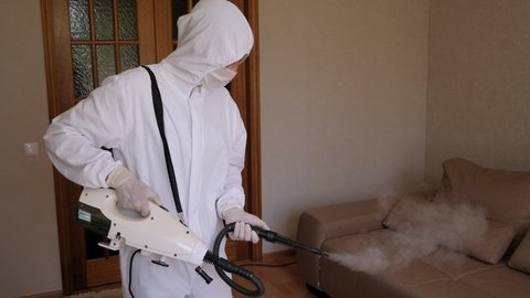 A man in a protective suit makes disinfection and decontamination from the coronavirus in the apartment with hot steam. Coronavirus disinfection.