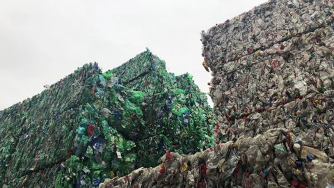 Low Angle View Of Pressed Cubes Of Plastic Bottles Stacked Outside In Recycling Plant