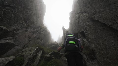 A man climbing a dangerous misty mountain gully on Tryfan in Snowdonia