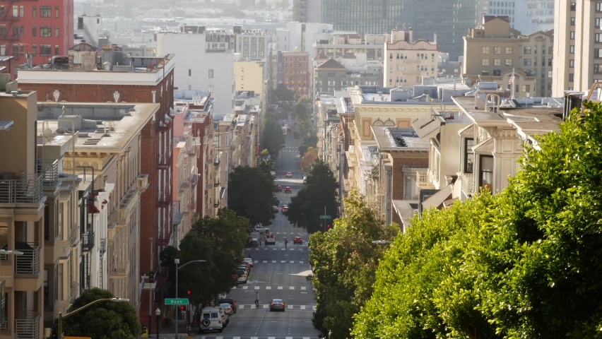Iconic hilly street and crossroads in San Francisco, Northern California, USA. Steep downhill road and pedestrian walkway. Downtown real estate, victorian townhouses abd other residential buildings.