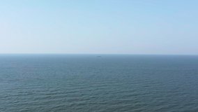 Aerial footage of a ship in an endless blue ocean on a sunny day.