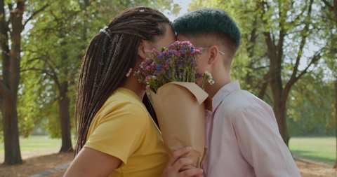 Two young women kissing, holding flowers, same-sex relationship, romantic date స్టాక్ వీడియో