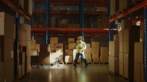 Worker Moves Cardboard Boxes using Hand Pallet Truck, Walking between Rows of Shelves with Goods in Retail Warehouse. Product Delivery Distribution Logistics Center. Side View Slow Motion