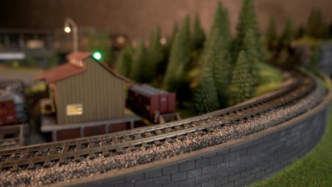 Miniature freight train moving on miniature railroad. Model of railway road with moving cargo train.