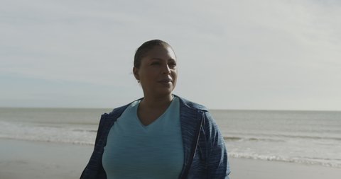 Portrait of Body positive mature black female model outdoors on beach, Plus size overweight Afro American woman looking at camera at sunrise
