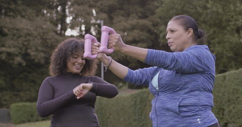 Black women sports training body positive with weights fitness instructor at outdoors gym in park, Plus size females exercising outdoors on sunny day