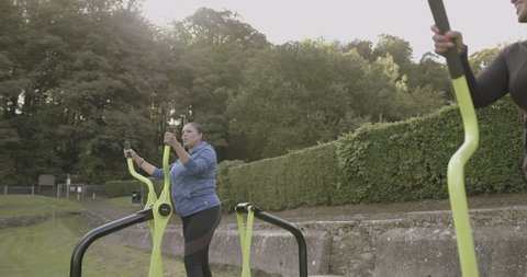 Two plus size females exercising at outdoors gym, overweight black women sports training body positive fitness exercise class