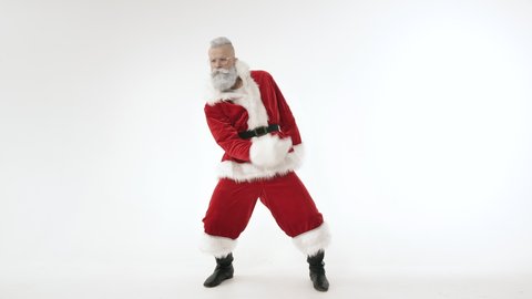 Active Cheerful Stylish Santa Claus Positively Dances, Haves Fun to Energetic Music Looking at Camera, Standing on White Background Indoors. Joyful Celebration Happy New Year, Merry Christmas Holidays
