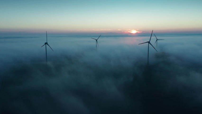 Wind turbines at sunrise in heavy fog. Wind farm generating green energy | Shutterstock HD Video #1060491043
