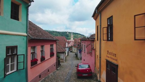 Sighisoara, Mures County / Romania - 08 04 2019: Drone aerial flight through tight alley rising up towards old church in Sighisoara , Romania