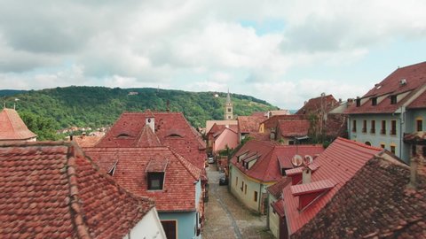 Sighisoara , Mures County / Romania - 08 04 2019: Backwards drone aerial flight through tight alley in ancient city of Sighisoara in Romania