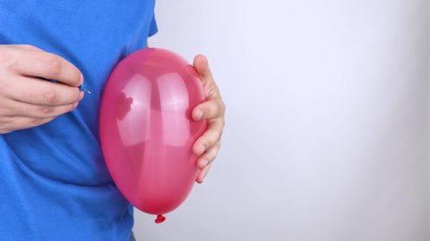 Conceptual video. The man holds a red ball near his belly, which symbolizes bloating and flatulence. Then he brings a needle to it to burst the balloon and thus get rid of the problem.