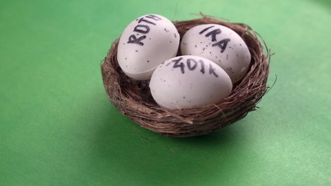 Conceptual composition. Pension savings. Three eggs with the inscriptions IRA, 401k, Roth lie in the nest and rotate against in the green background. Close-up