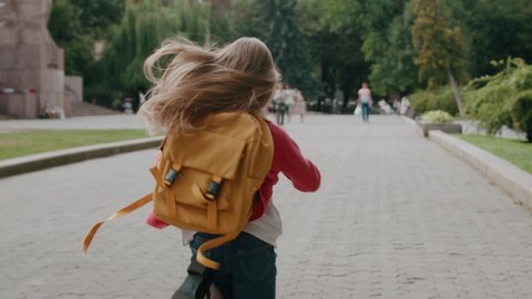 Shot back little girl kid with a backpack runs hurrying to school. Study adventure walk knowledge child pupil. Primary kindergarten. Close up. Slow motion