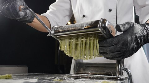Traditional Italian cuisine. making pasta on machine for cutting pasta. Slow motion. Dough slicing machine. pasta making machine to make fresh spinage tagliatelle. Full hd