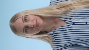 Blonde young woman misunderstanding something on blue background. She showing this emotion on face and in gesture. Video with Vertical Screen Orientation 9:16