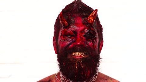 Halloween in blood. Devil head with horns in blood, bloody face. Scary horrorwith spooky monster. Demon or satan. Fantasy art project for holiday. Realistic gothic monster zombie
