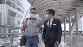 Business people Caucasian with Asian man office worker colleague wearing face mask for protect covid-19 virus walking together on office district and discussing business project with using smartphone. - Powered by Shutterstock - Get 15% off with code: PIKWIZARD15