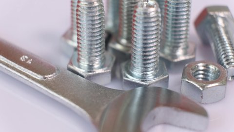 Rotating group of galvanized metallic screws , wrench and nut close-up.