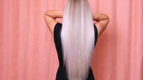 Slow motion shooting of the long blond hair of a young lady, backside view. Haircare concept