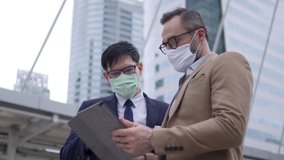 Business people Caucasian with Asian man colleague partnership wearing protective face mask for protect covid-19 virus discussing business project plan with using digital tablet computer in the city - Powered by Shutterstock - Get 15% off with code: PIKWIZARD15